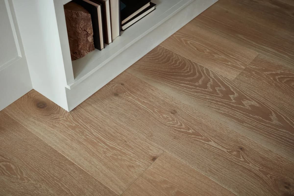 Extra-wide white oak engineered hardwood planks with pronounced grain, shown beside white built-in shelving stocked with books