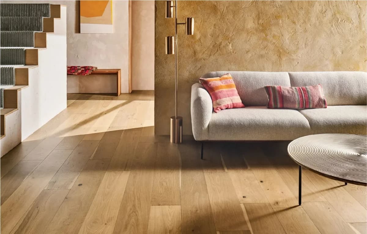 Anderson Tuftex engineered white oak flooring in Orchard Smooth fills a bright, open living room beside a staircase.