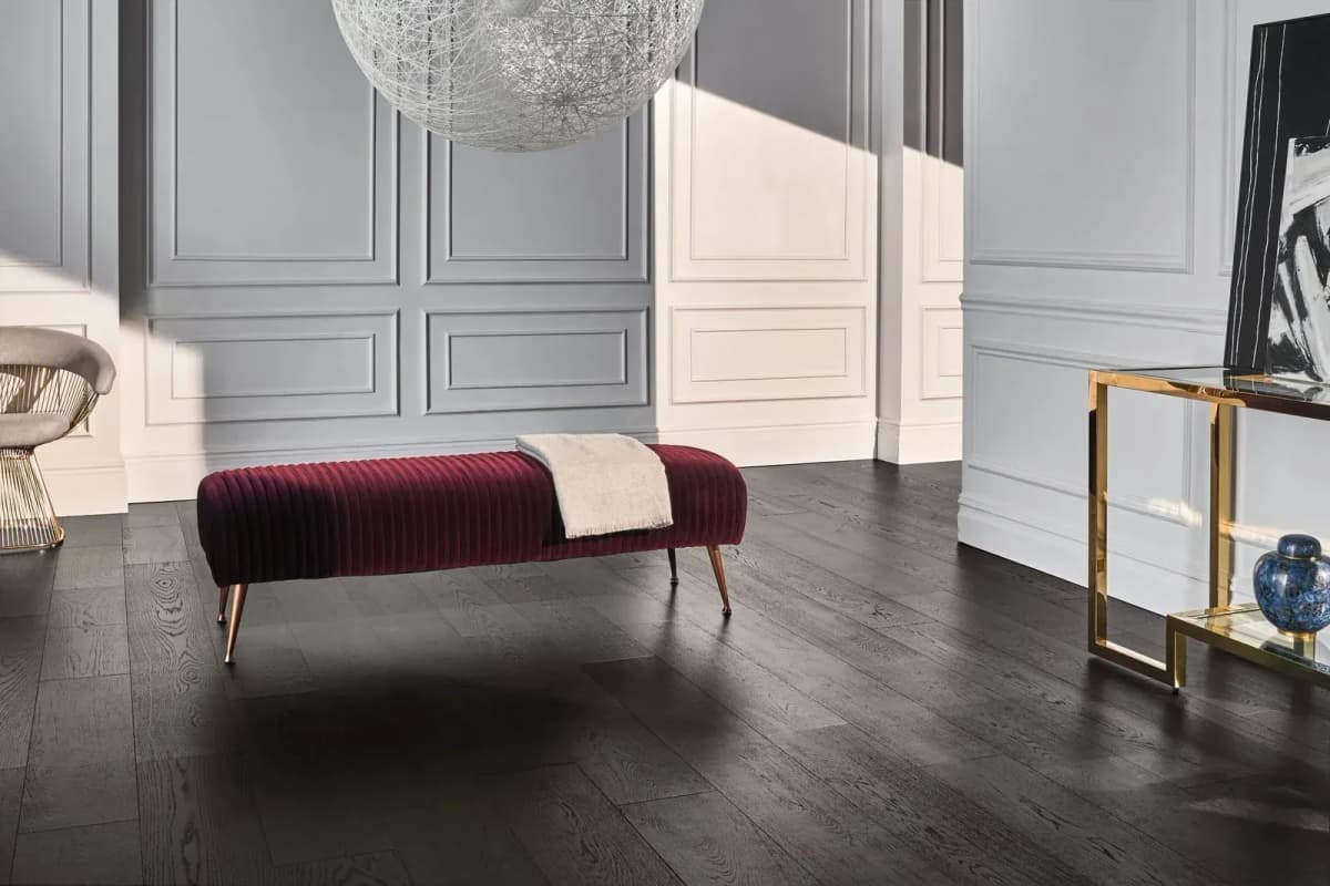 Anderson Tuftex Ravenwood engineered hardwood in a dark espresso tone spans an open, sunlit room with paneled walls.