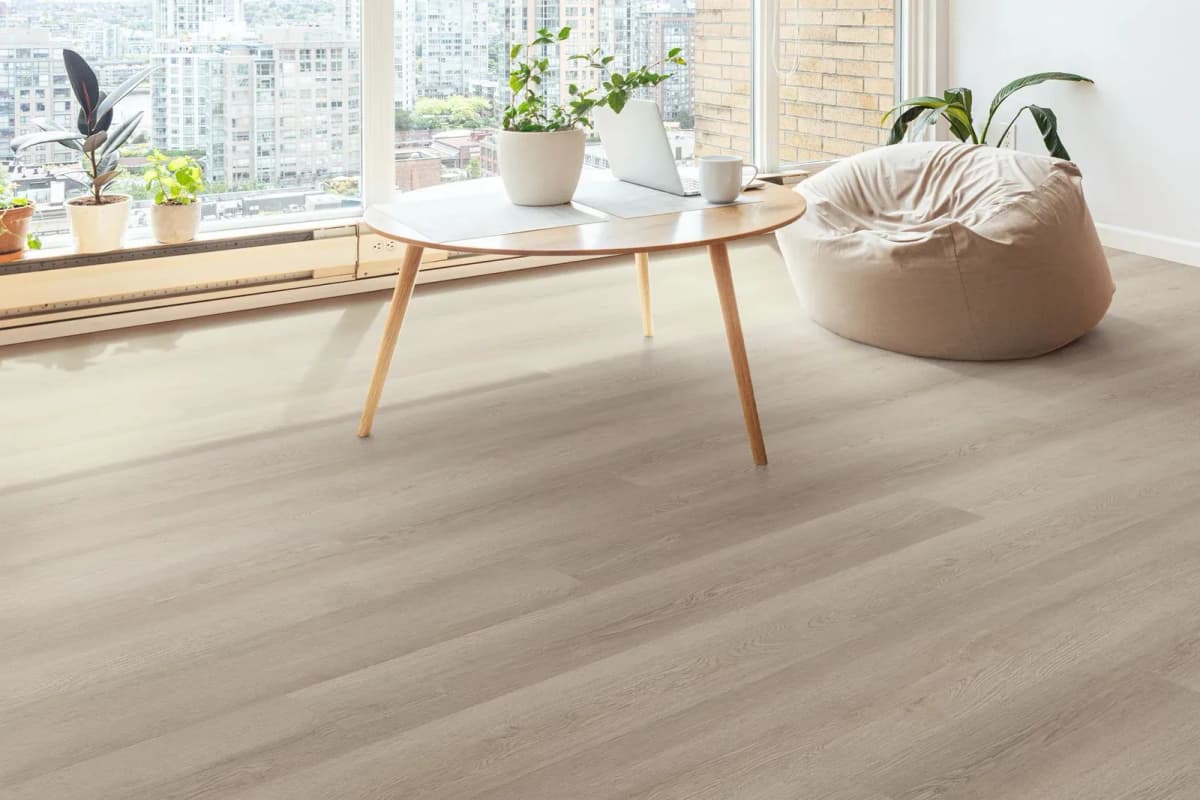 Pampas luxury vinyl plank flooring in a high-rise condo with a round wood table, a beanbag chair and a wall of windows over the city