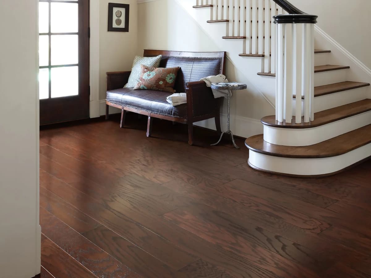 Shaw Albright Oak 5 engineered hardwood in Coffee Bean in an entryway at the foot of a curved staircase with wood treads and white risers