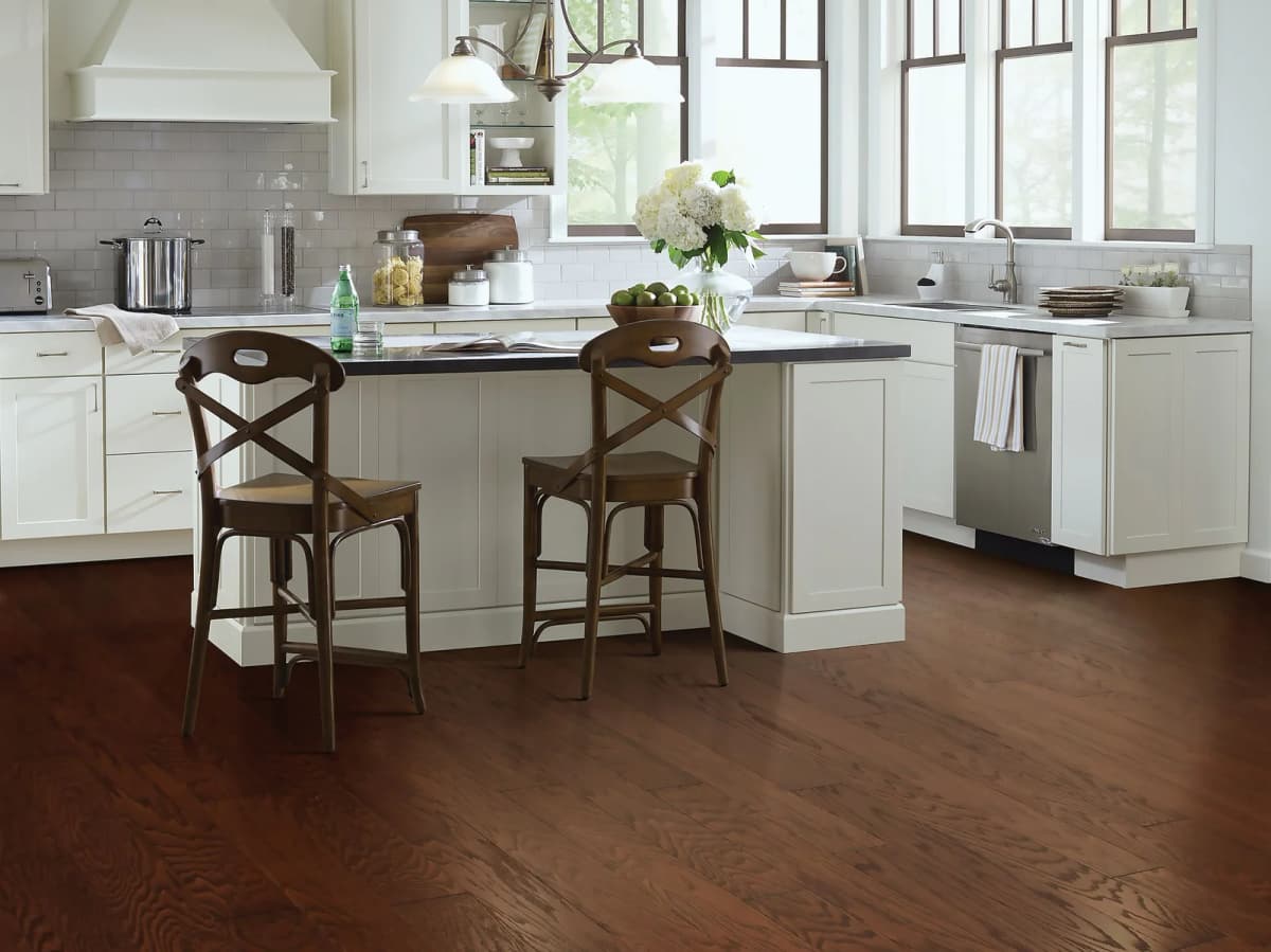 Hazelnut oak flooring in a kitchen with a center island and two wood bar stools