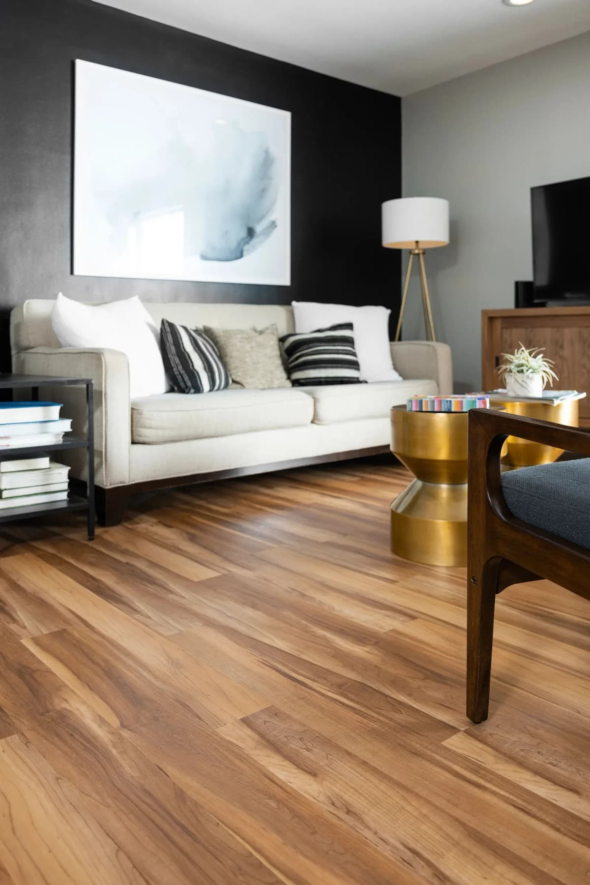 Warm Red River Hickory luxury vinyl plank flooring in a staggered layout, filling a modern living room with a cream sofa and wood accent chair