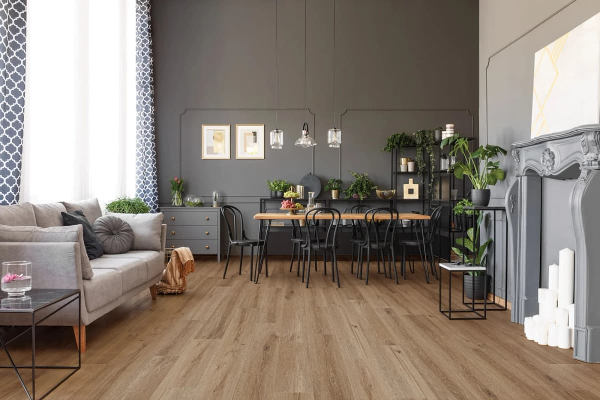 Wide, long Grande Goldin Oak luxury vinyl planks spanning an open living and dining room with a wood table and black metal chairs
