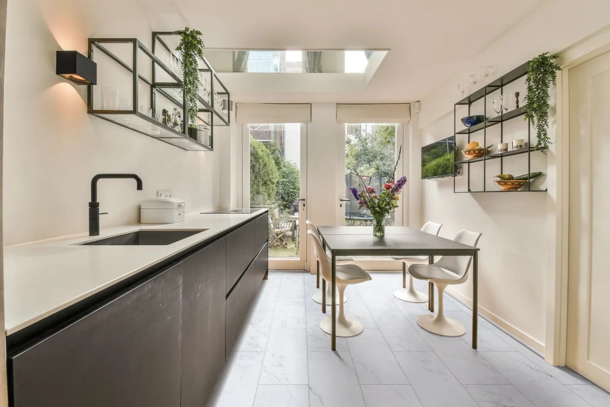 Light gray marble-look luxury vinyl tile flooring with visible grout lines running through a kitchen and dining nook with dark cabinetry and glass garden doors