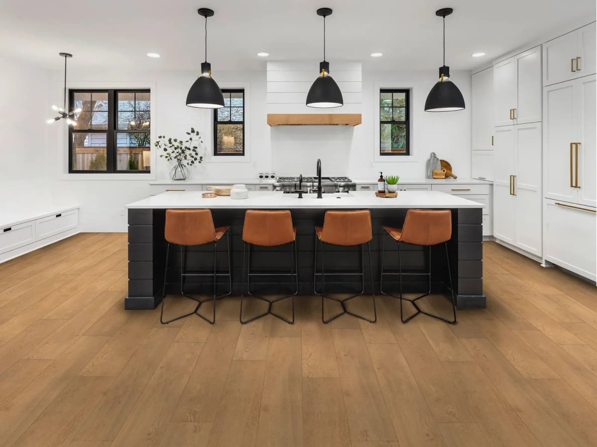 Fairhaven Oak COREtec Pro flooring in a modern kitchen with a black island and pendant lighting