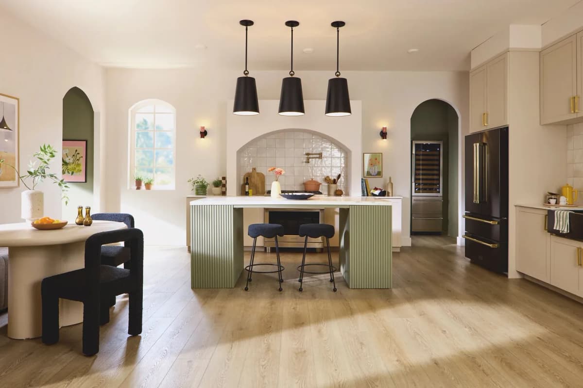 Natural Linen Oak luxury vinyl plank flooring in an open kitchen and dining area with a green fluted island, black pendant lights, and cream cabinetry
