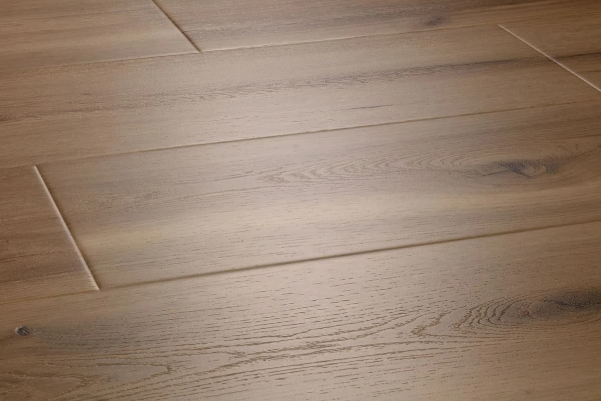 A COREtec Parchment Oak plank shows a visible beveled edge and varying board widths in close, angled light.