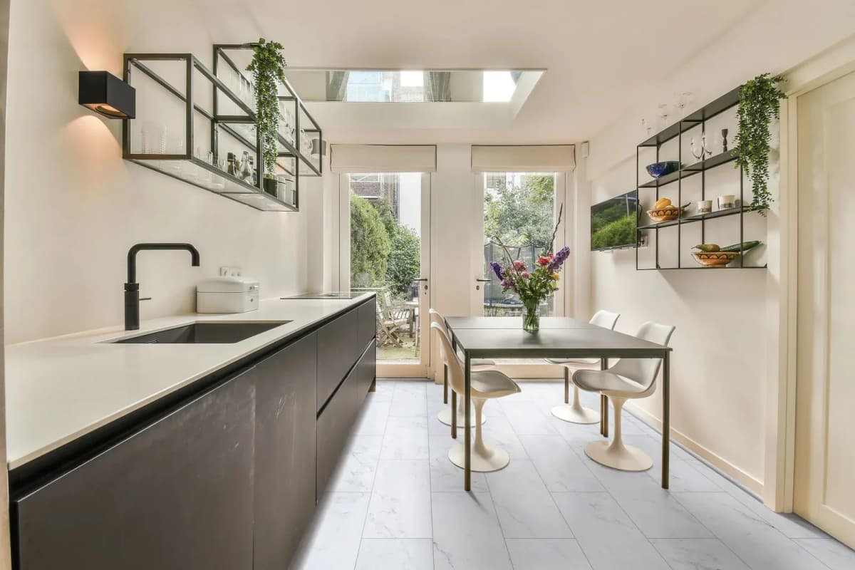 COREtec Plus Tile in Bianco Marble runs through a kitchen and dining space with black cabinetry and glass garden doors.