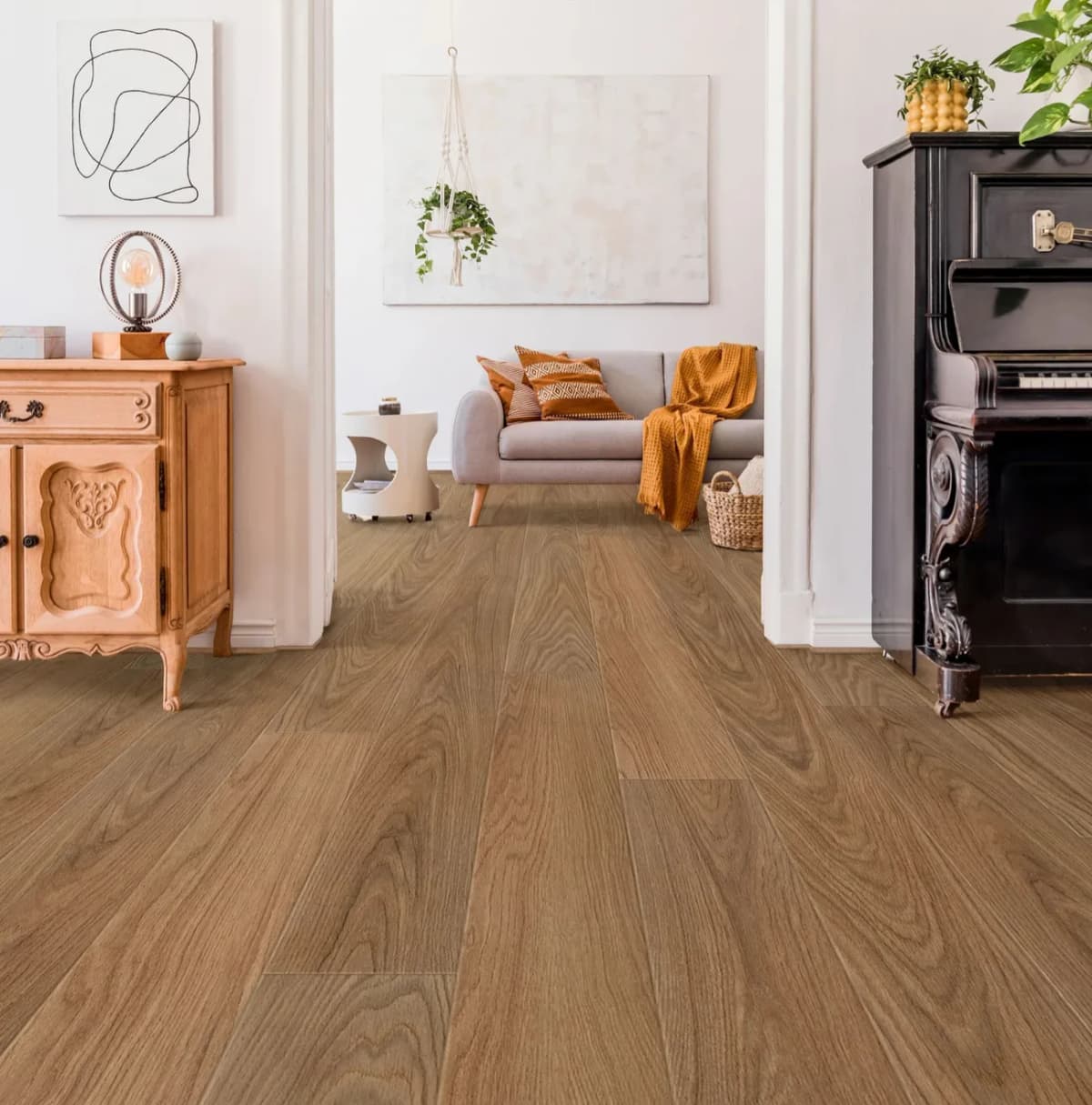 An upright piano and an antique wood cabinet on warm-toned luxury vinyl plank flooring in a bright living room