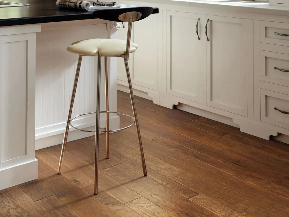 Warm Sunset Pebble Hill hickory hardwood flooring in a kitchen with white cabinetry and a bar stool