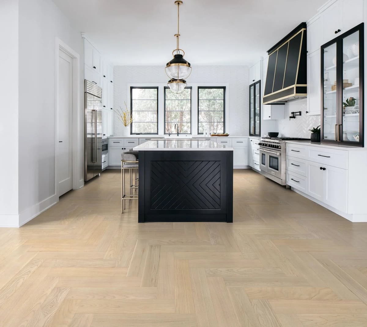 Anderson Tuftex European Ash herringbone flooring in Metro laid across a bright white kitchen with a black island and brass pendants