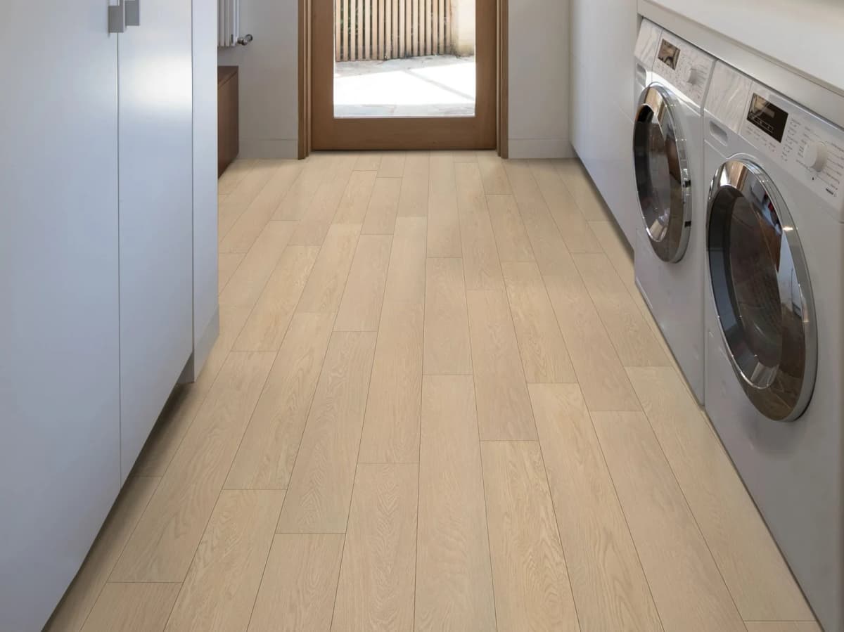 Light wood-look LVP flooring running through a laundry room with a side-by-side washer and dryer