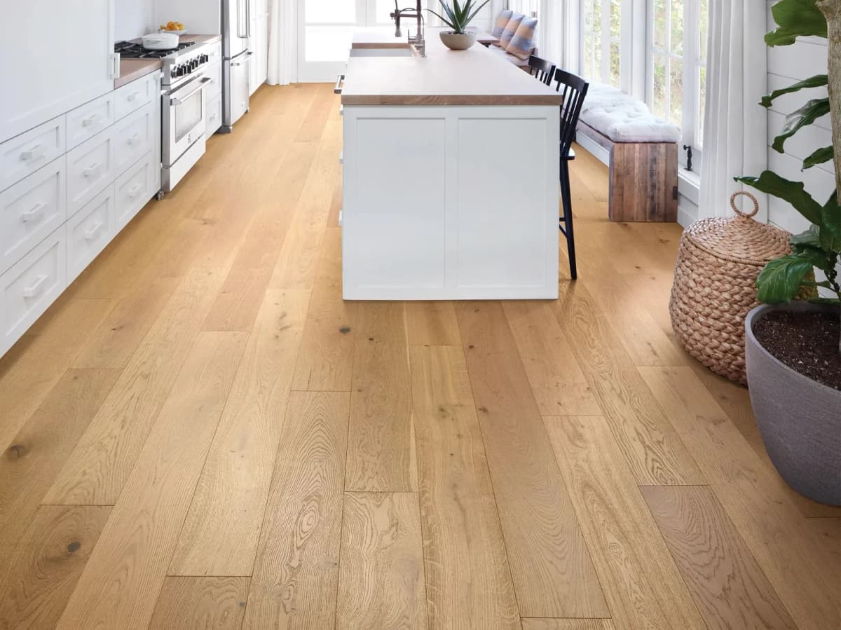 Shaw Expressions white oak flooring in Harmony spans a bright kitchen from cabinetry to island, wall to wall.