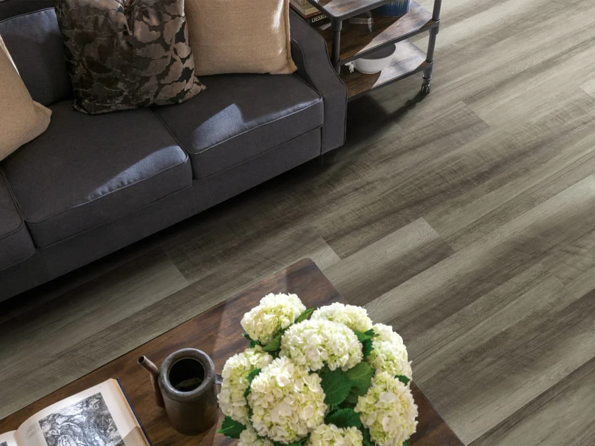 Shaw wood-look vinyl plank flooring in a living room with a dark sofa and cart
