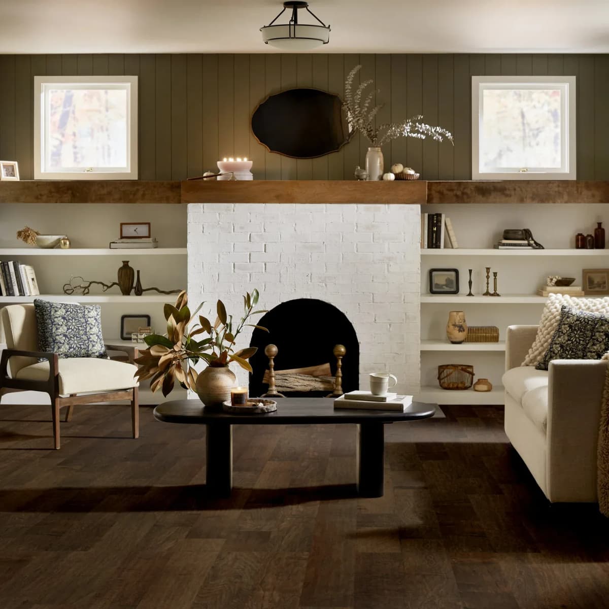 Dark maple hardwood flooring by Shaw stretches wall to wall through a symmetrical living room with a brick fireplace.