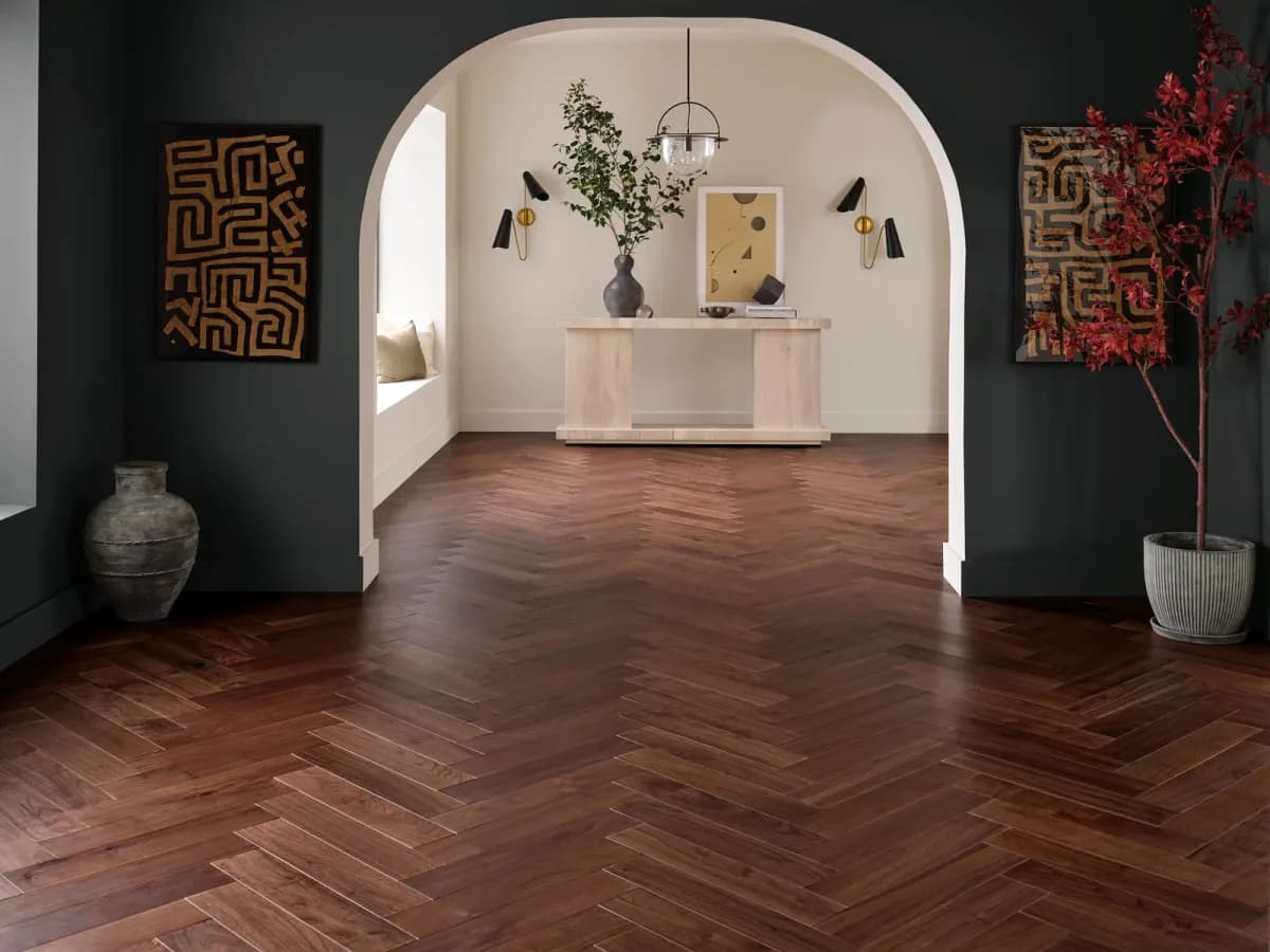 Anderson Tuftex American walnut flooring in a rich brown herringbone pattern fills an archway entry.