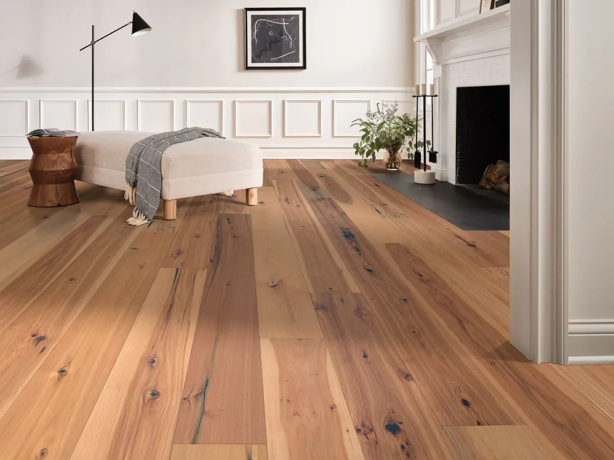 Honey-toned pecan engineered hardwood planks in a living room with a white brick fireplace.