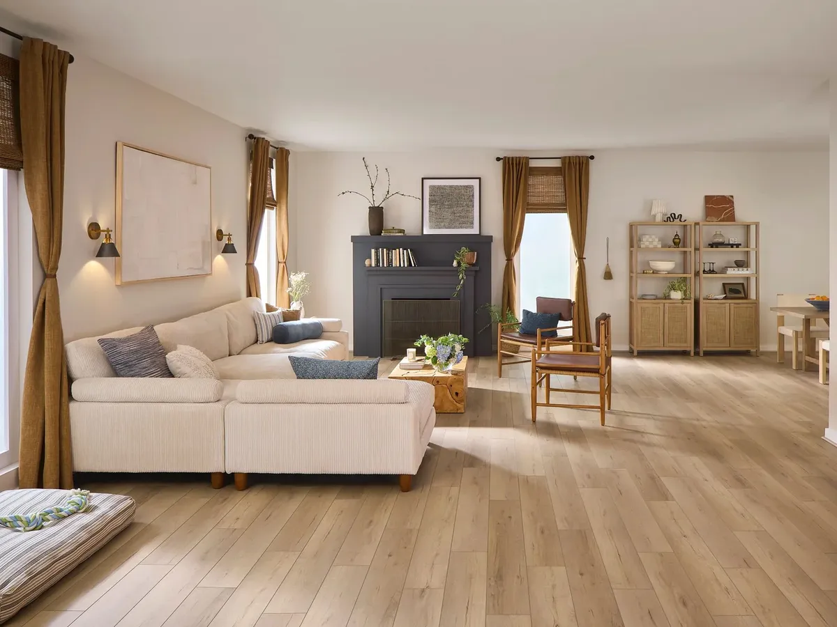 A dark painted fireplace overlooks light golden-brown luxury vinyl plank flooring in a living room with a cream sectional.