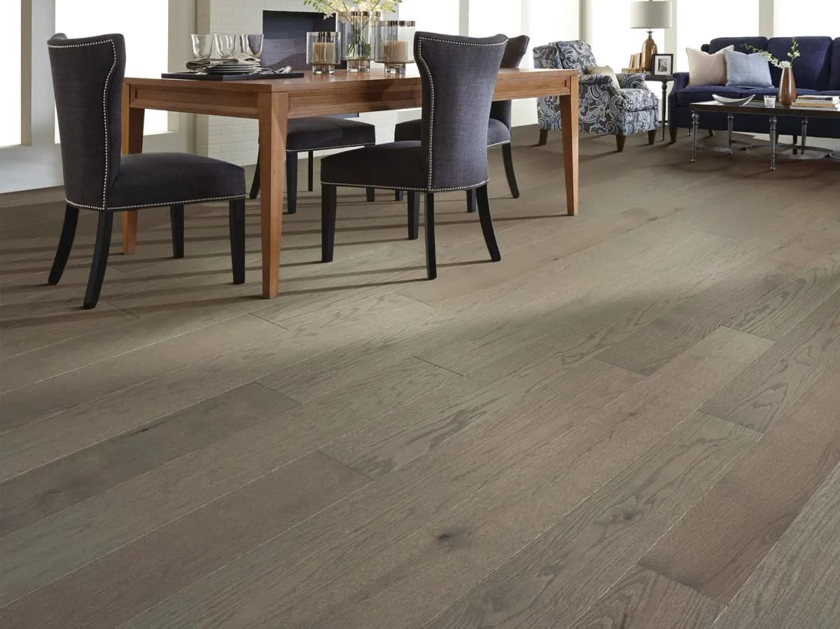 Light gray-brown oak plank flooring runs through an open dining and living room.
