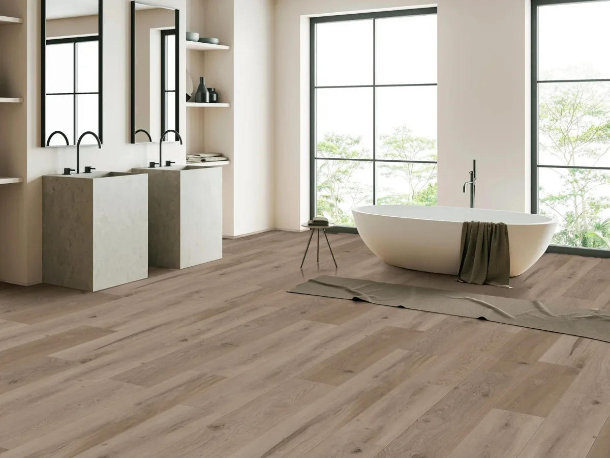 A freestanding tub sits on gray-brown luxury vinyl plank flooring in a spa-style bathroom.