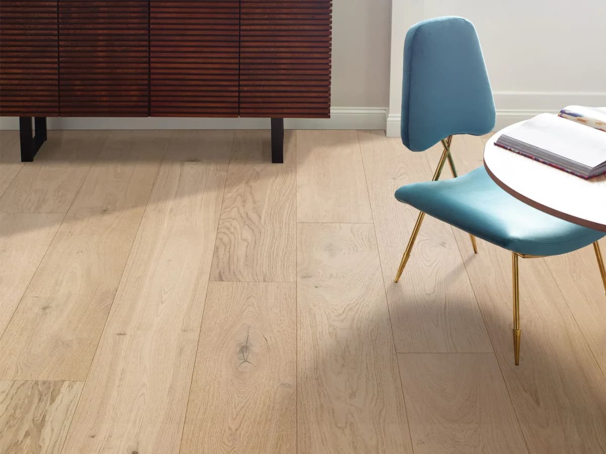 Anderson Tuftex pale white oak plank flooring with a slatted wood credenza and teal chair.