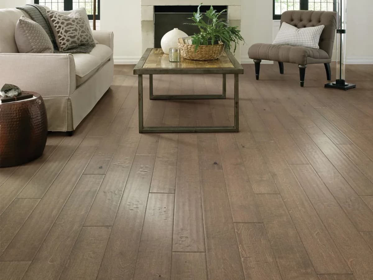 Shaw birch engineered hardwood plank flooring in a warm taupe tone fills a living room.