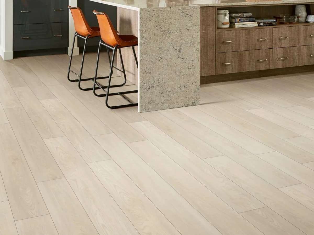 Shaw luxury vinyl plank flooring in a light oak tone fills a modern kitchen.