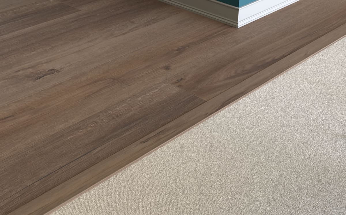A baby threshold capping the finished edge of a plank floor where it ends against carpet