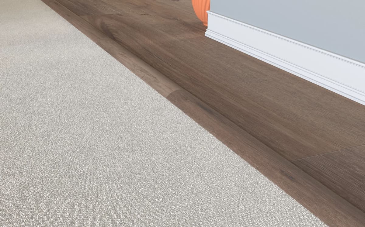 An overlap reducer tapering a dark plank floor down to the lower carpet beside it